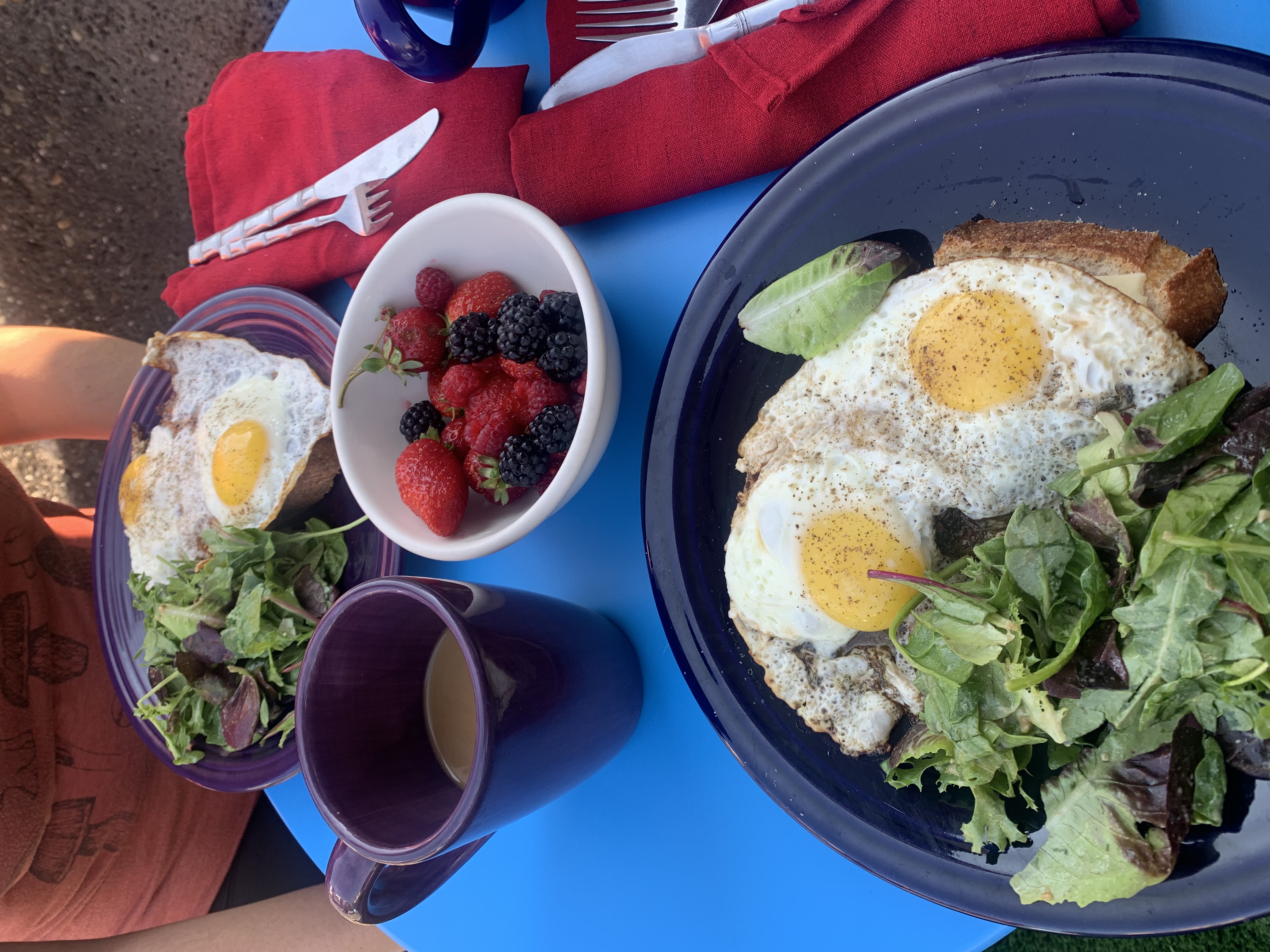 Uitsmijter — a classic Dutch open-faced breakfast with fried eggs on toast, salad, fresh berries, and coffee on a blue table
