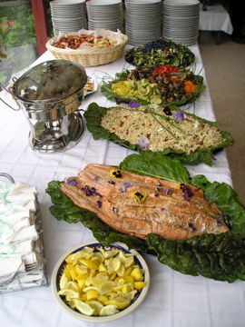 Full catering buffet spread with whole roasted fish, salads, and a chafing dish