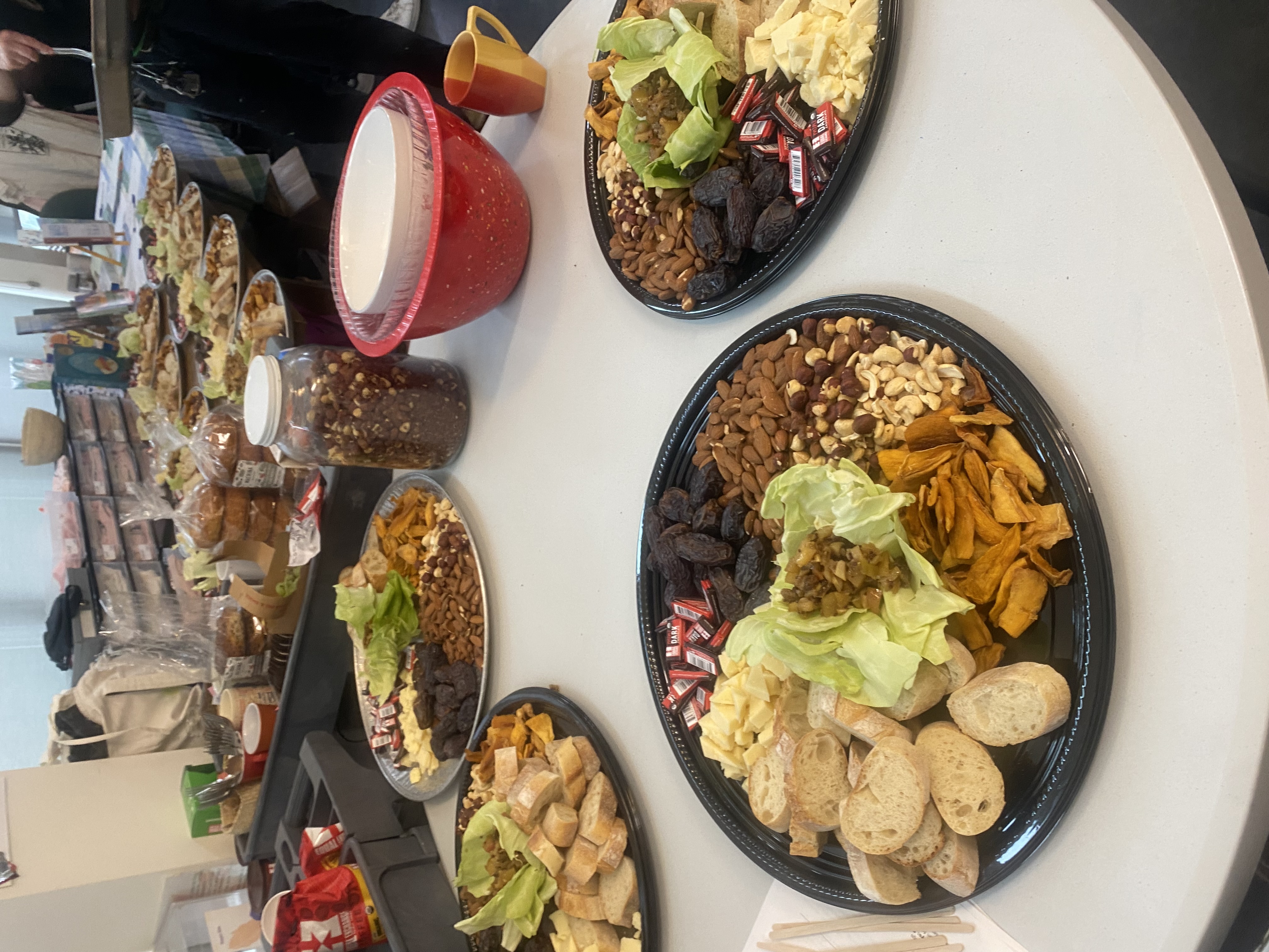 Rows of identically plated catering spreads with bread, cheese, dates, and nuts, ready to serve