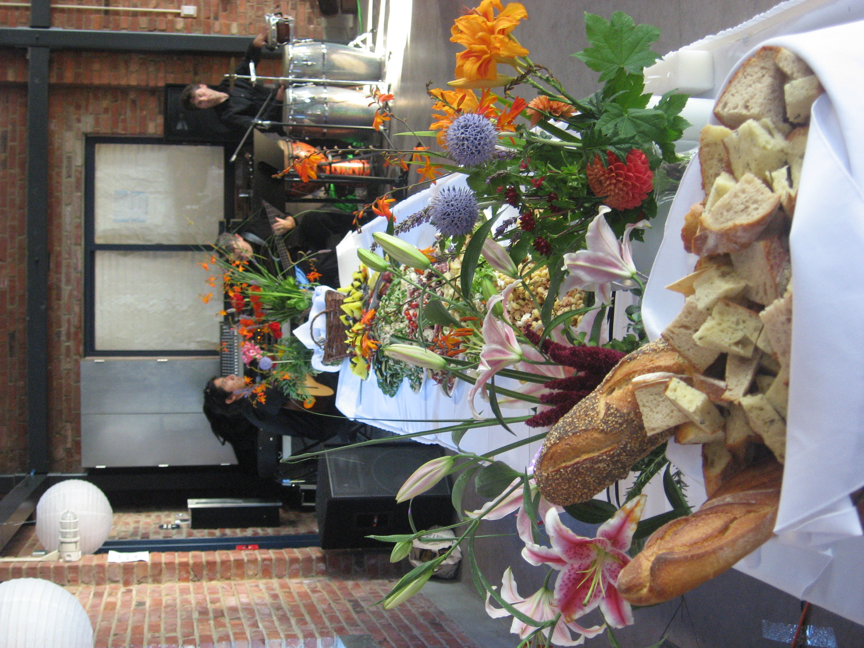 Catering table with bread, flowers, and a live band at an event